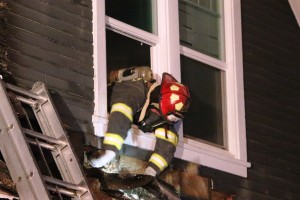 A firefighter removes siding.Colby house fire 2